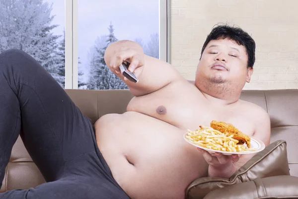 Overweight man watches tv in winter season