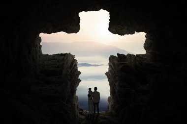 Family standing inside cave shaped a cross clipart