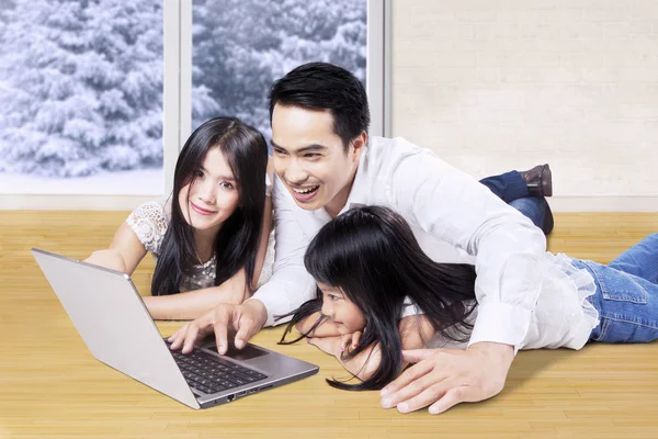 Leuke familie laptop gebruikt op houten vloer — Stockfoto