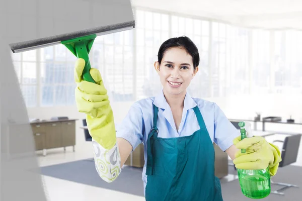 Happy housemaid cleans the mirror — Stock Photo, Image