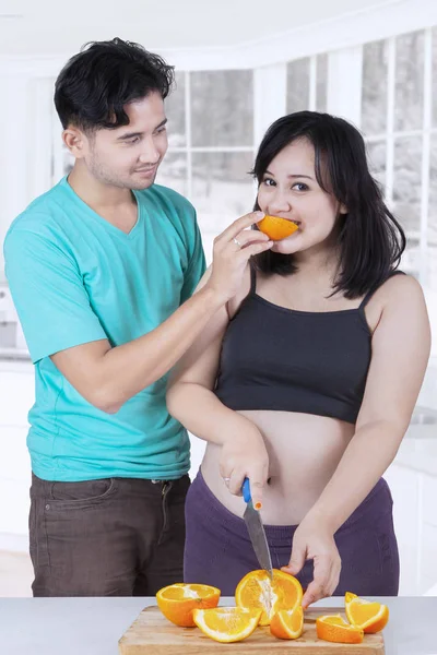 Koca karısına turuncu meyve beslenme — Stok fotoğraf