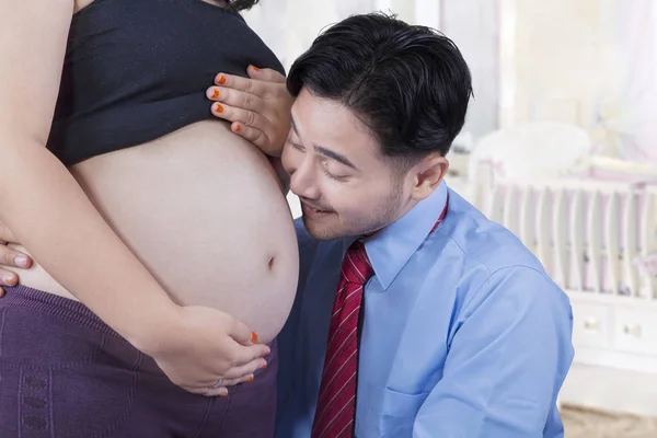 Manžel úsměvy na těhotné bříško — Stock fotografie