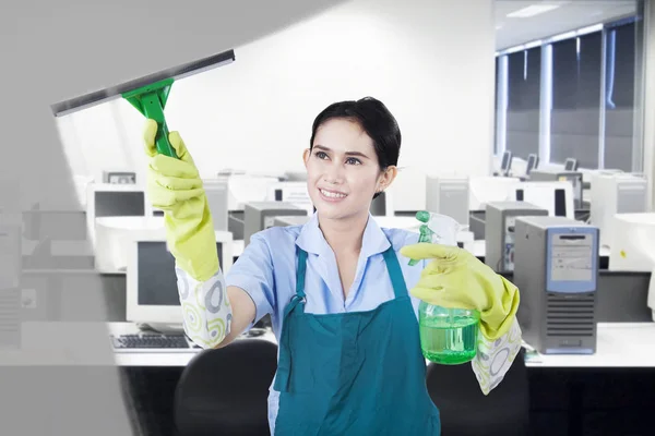 Pretty maid cleaning a mirror — Stock Photo, Image