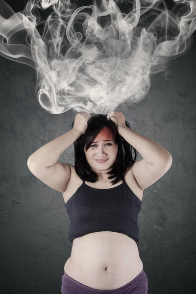 ストレスの多い女性は、煙と彼女の頭を保持しています。 — ストック写真