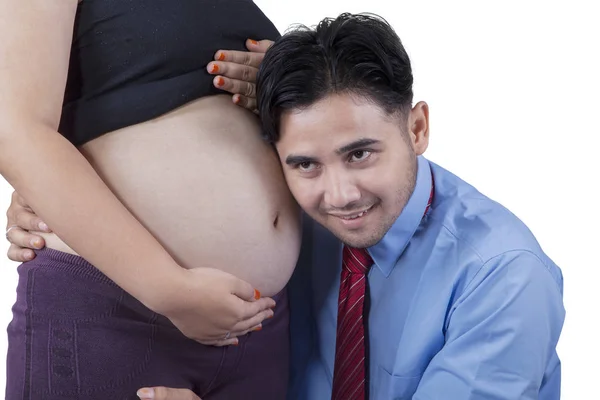 Joven padre escuchando vientre embarazada — Foto de Stock