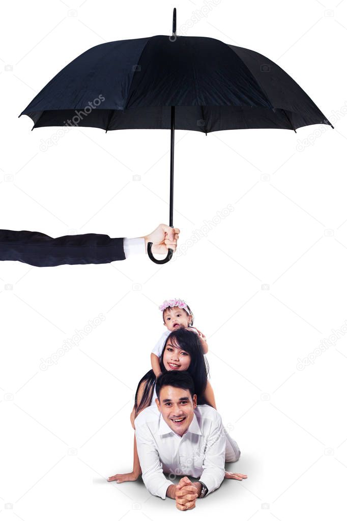 Happy family lying in studio under umbrella