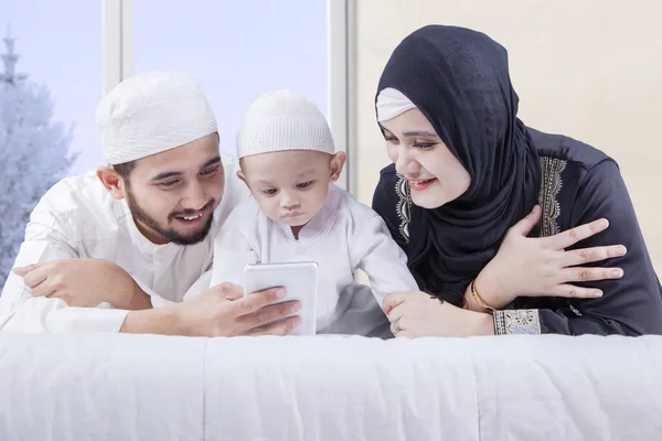Família árabe olhando para smartphone na cama — Fotografia de Stock