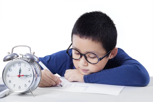 Niño estudiando con despertador en el escritorio — Foto de Stock