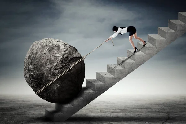 Businesswoman dragging stone on ladder — Stock Photo, Image