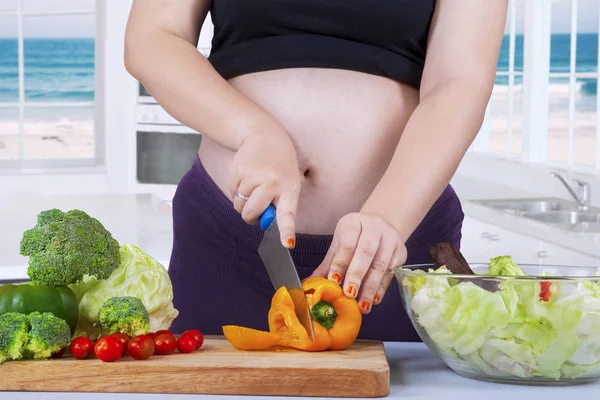 Expectant woman cuts fresh paprika — Stock Photo, Image