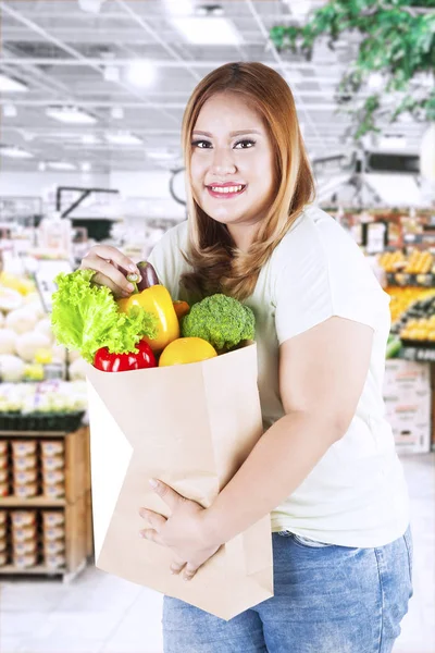 脂肪の女性が店で野菜を保持します。 — ストック写真