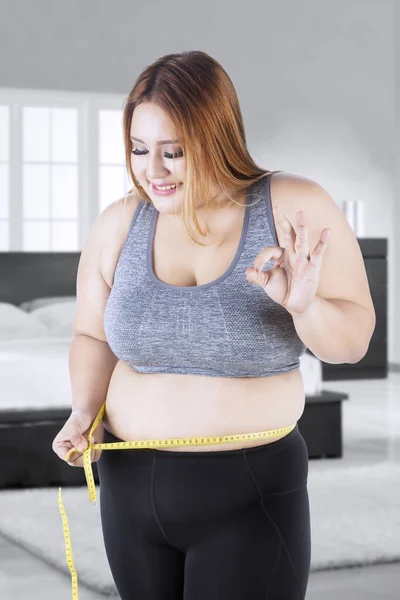 Счастливая толстая женщина измеряет свой живот — стоковое фото