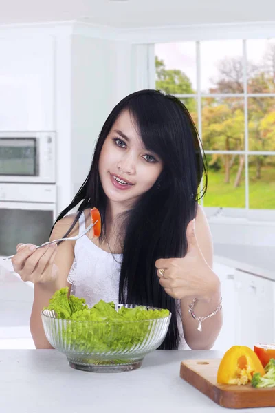 Glückliche Frau genießt Salat in der Küche — Stockfoto