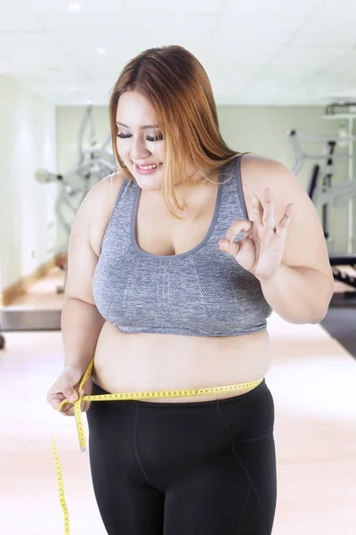 Obese woman measures her belly — Stock Photo, Image