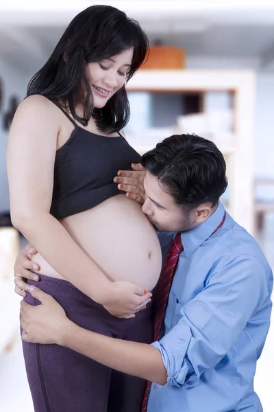 Jovem marido beija barriga grávida — Fotografia de Stock