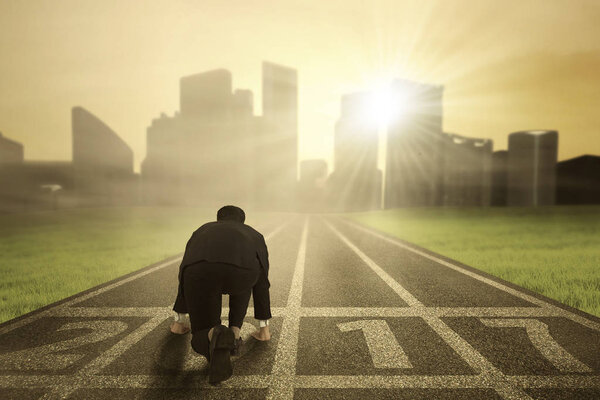 Businessman ready to run on running track
