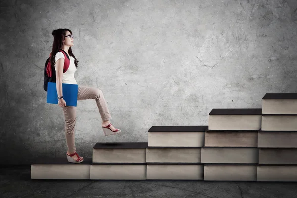 Estudiante universitario subiendo la escalera de libros — Foto de Stock