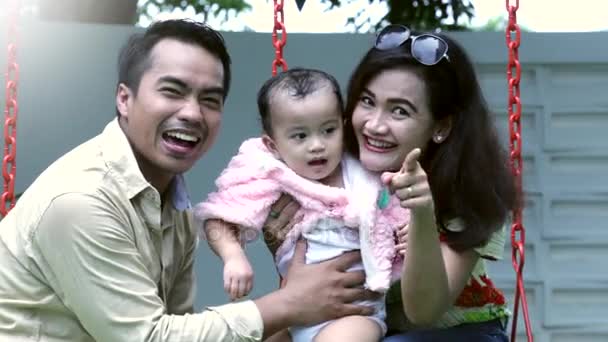 Азиатская семья улыбается на качелях — стоковое видео