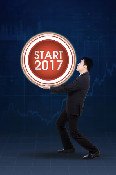 Asian businessman carrying big start button — Stock Photo, Image