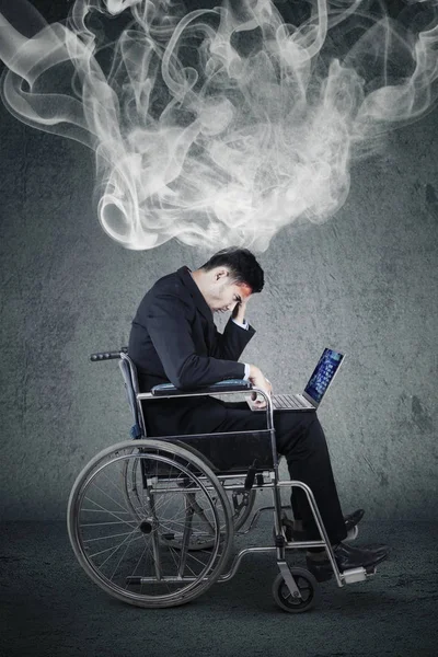 Empresario sentado en silla de ruedas con humo — Foto de Stock