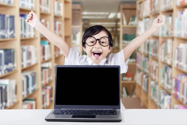 Bambino allegro con schermo del computer portatile vuoto in biblioteca — Foto Stock