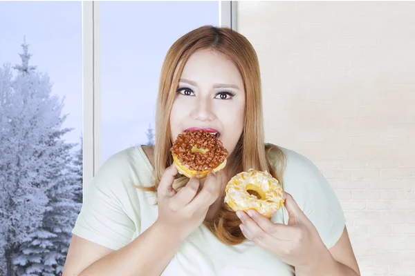 Mulher gorda comendo dois donuts — Fotografia de Stock