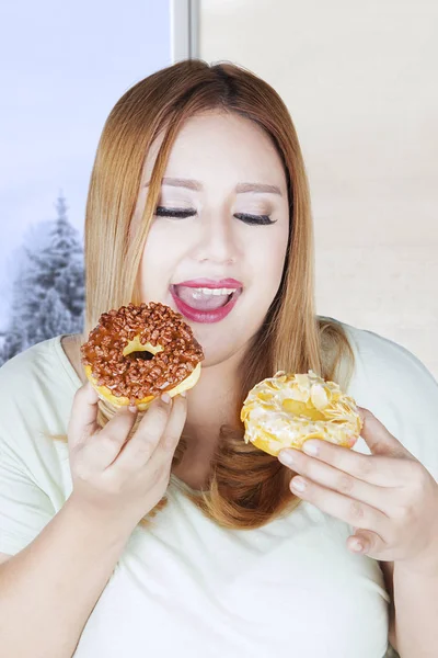 Dikke vrouw bedrijf twee donuts — Stockfoto