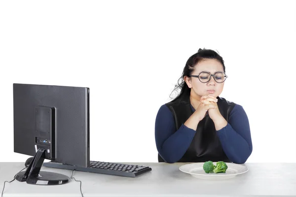 Fet kvinna ber innan äter broccoli — Stockfoto