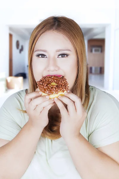 Obézní ženy sní koblihu doma — Stock fotografie