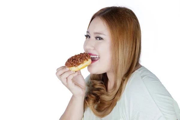Smiling woman eats donut in studio — Stock Photo, Image
