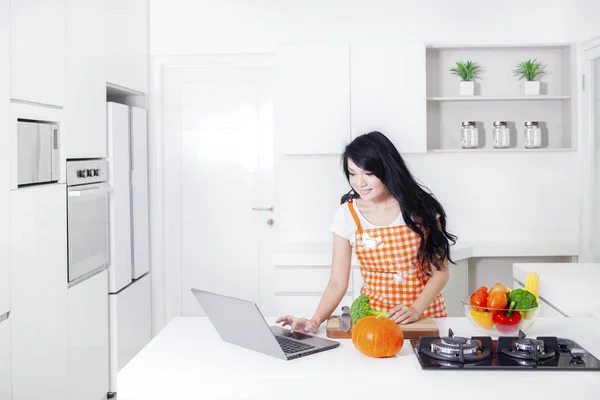 Nő főzés és használ laptop konyha — Stock Fotó