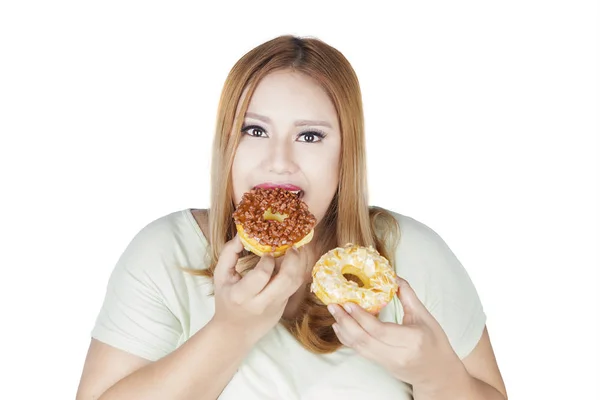 Mulher come dois donuts na mão — Fotografia de Stock