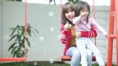   Anne ve çocuğu salıncakta sabun köpüğü oynamak