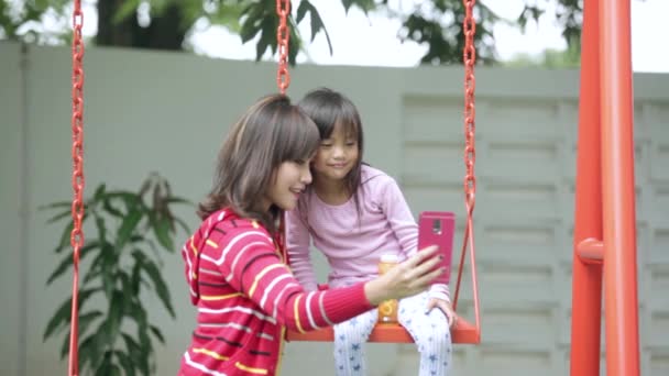 Мати і дитина приймають селфі на гойдалках — стокове відео
