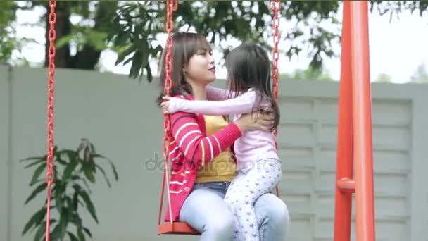 Pretty woman kissing her child on swing — Stock Video