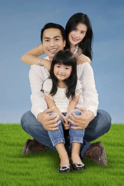 Fröhliche Familie sitzt auf dem grünen Gras — Stockfoto