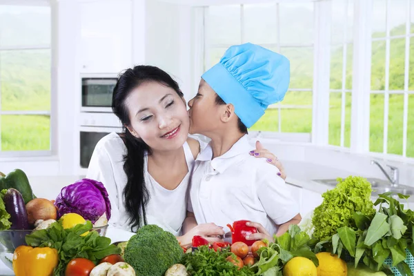 Enfant embrasser sa mère tout en cuisinant — Photo
