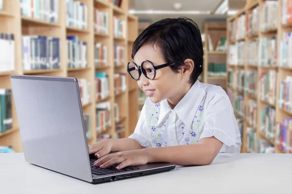 Cleveres Mädchen benutzt Laptop auf Schreibtisch in Bibliothek — Stockfoto