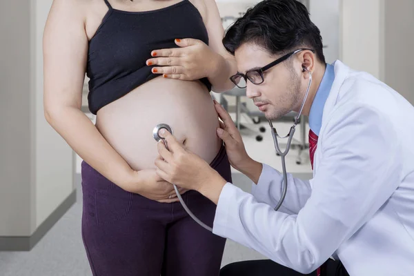 Doctor listening pregnant woman's belly — Stock Photo, Image