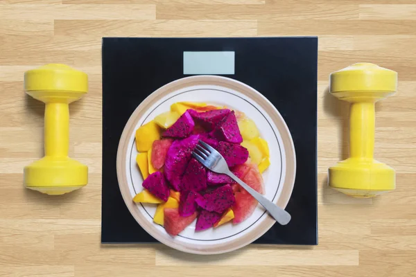 Frutas com escala e halteres na mesa — Fotografia de Stock