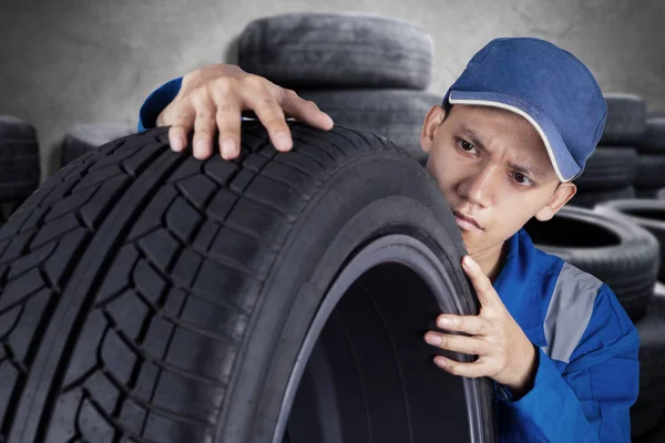 Mecânico masculino com um pneu velho — Fotografia de Stock
