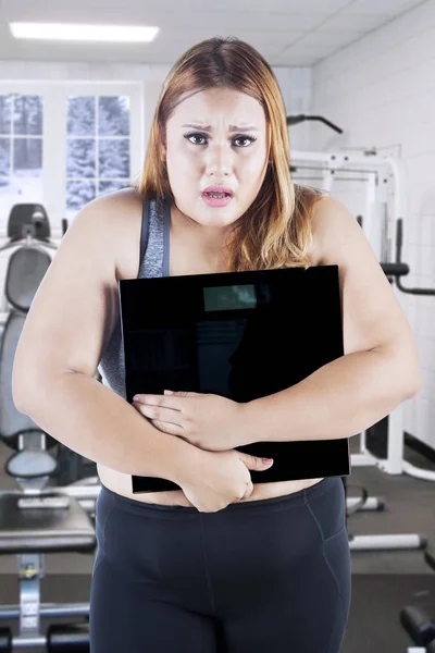 Mujer obesa con escala de peso en el gimnasio — Foto de Stock
