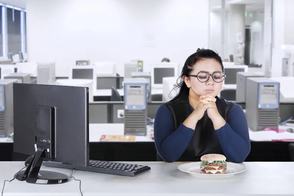 Бізнес-леді надмірної ваги вага вагається їсти бургер вдома — стокове фото