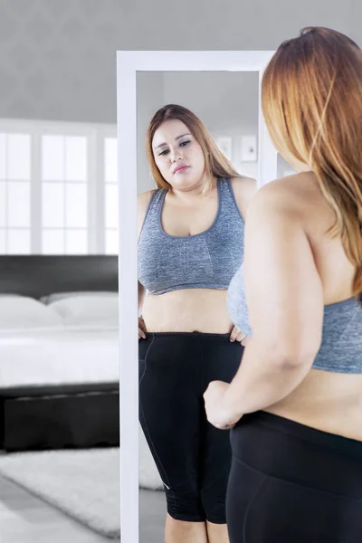 Overgewicht vrouw met de spiegel in de slaapkamer — Stockfoto