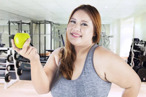 Mujer sostiene una manzana en el gimnasio — Foto de Stock