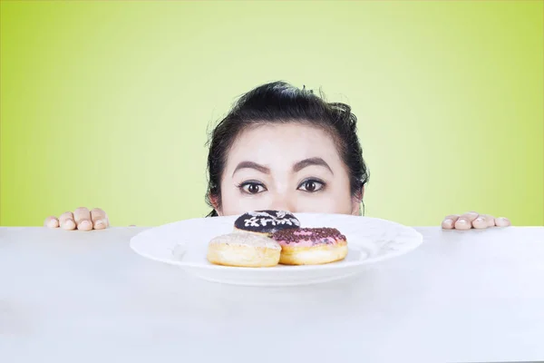 Mulher olhando para donuts na mesa — Fotografia de Stock