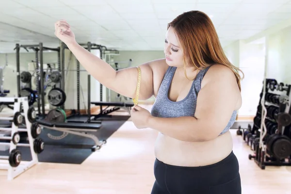 Mujer medir su brazo en la sala de gimnasio — Foto de Stock