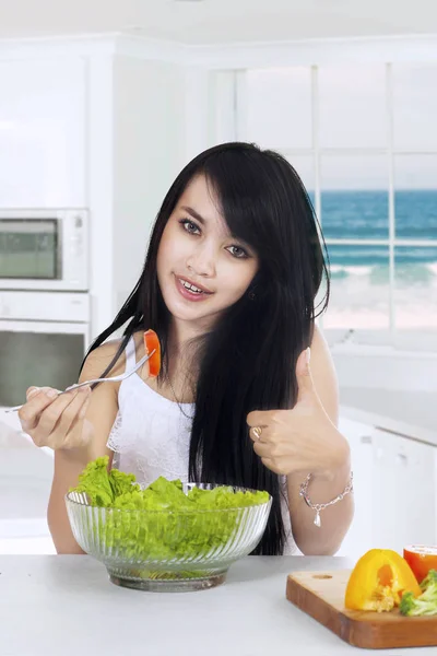 Jonge vrouw geniet van salade in keuken — Stockfoto