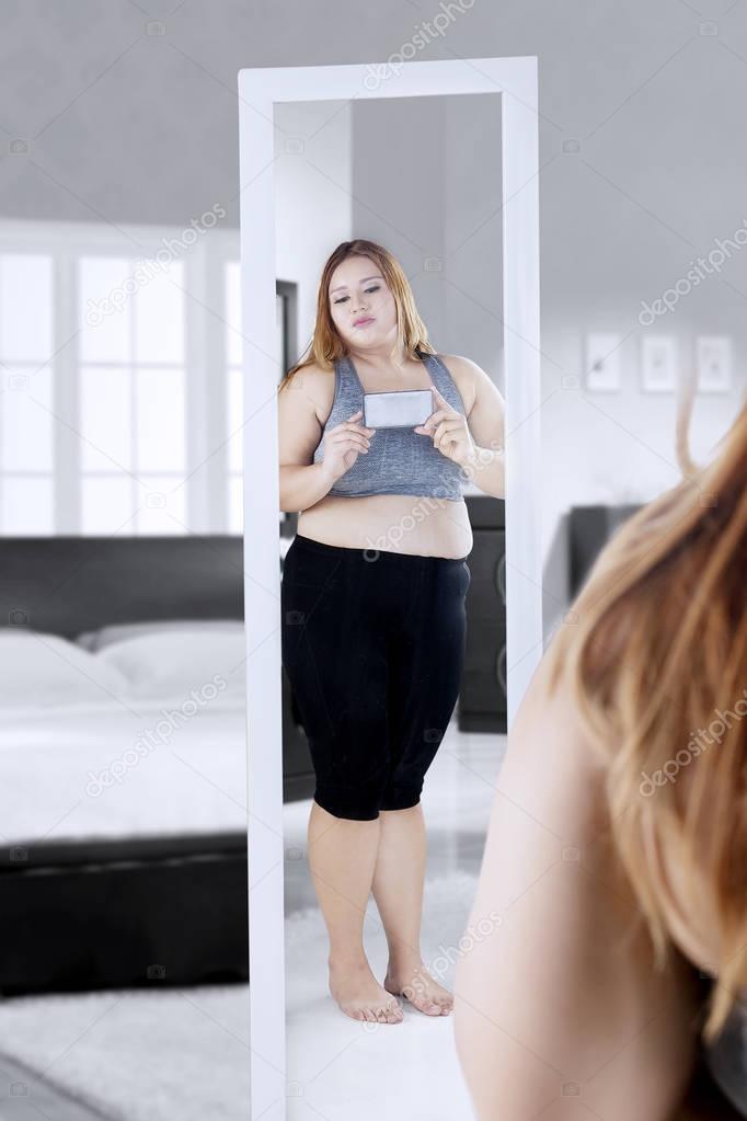 Overweight woman taking picture in the bedroom