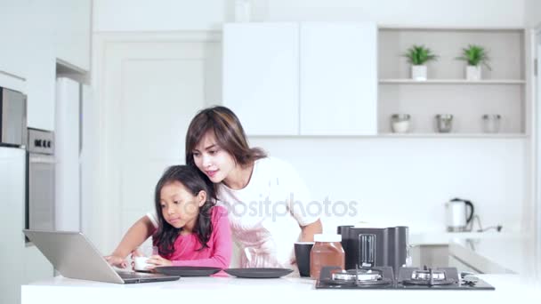 Ребенок и мать используют ноутбук на кухне — стоковое видео